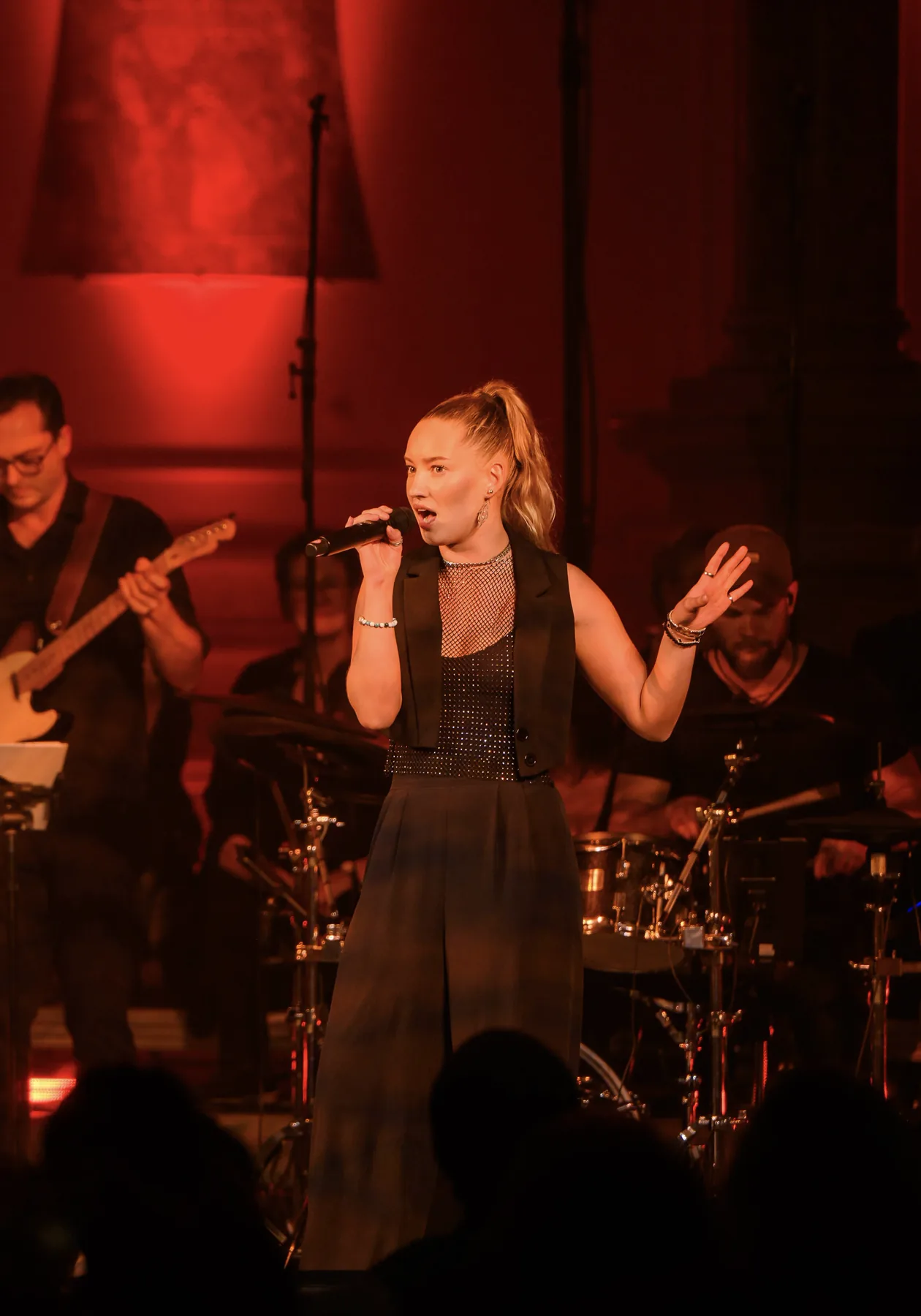 Jessie Rennings singt live auf der Bühne mit Band in rotem Licht